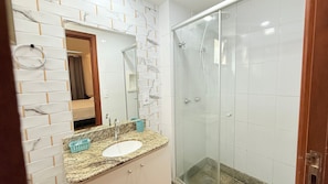 A bathroom with a glass shower enclosure, a sink with a marble countertop, and a mirror above the sink. - Diamond Beach (Vila Velha)