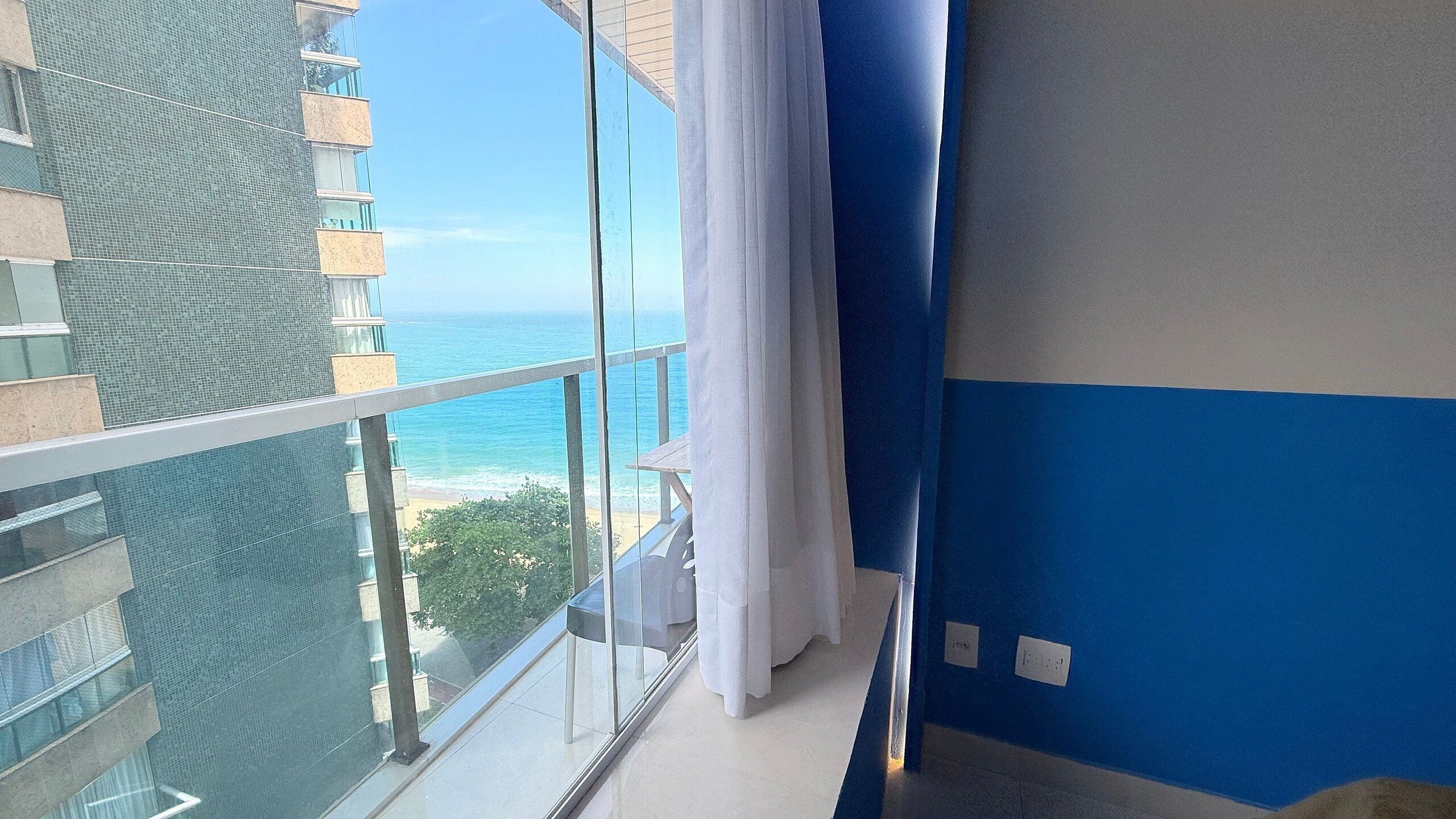 Un balcon avec vue sur l’océan et un bâtiment doté d’une façade en treillis.