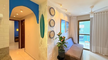 Un vestíbulo de hotel con diseño moderno, que cuenta con un gran ventanal con vistas a la ciudad, una zona de estar con sofá y una planta en maceta, además de decoración mural.