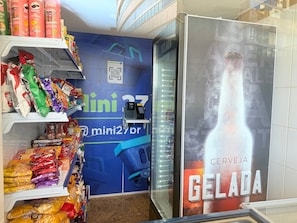 A snack display with various packaged snacks and a QR code on a blue wall. - Diamond Beach (Vila Velha)