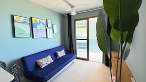 A room with a blue sofa, a ceiling fan, and large green leaves. - Diamond Beach (Vila Velha)
