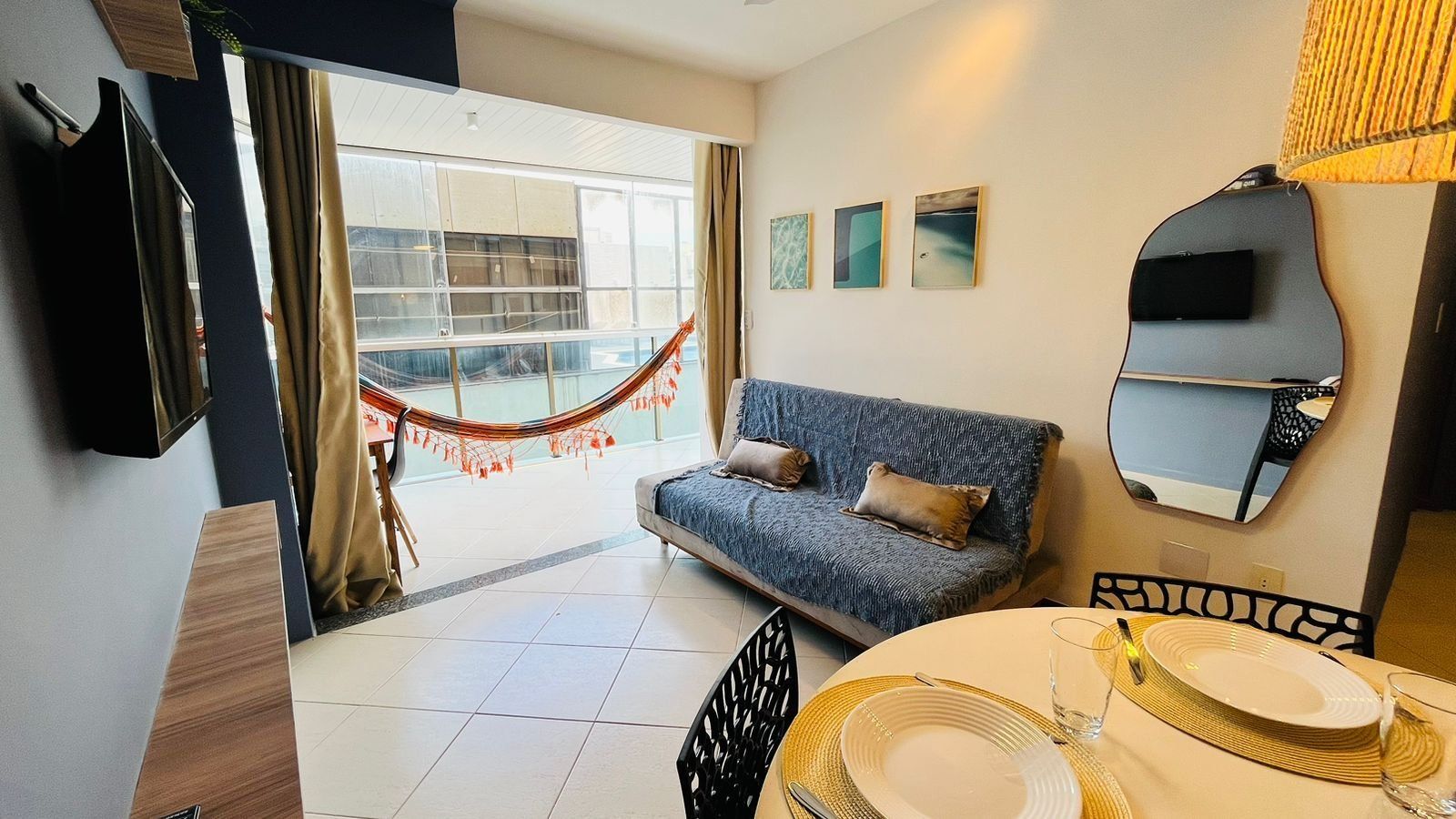 Una habitación de hotel moderna con sofá, mesa de comedor y una hamaca junto a la ventana.