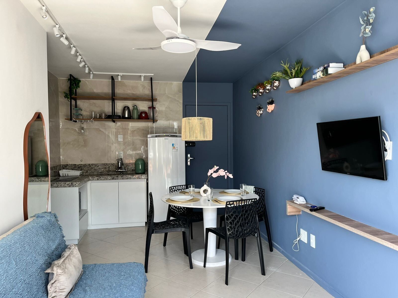 Una cocina moderna con comedor, ventilador de techo y televisor montado en la pared.