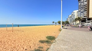 Una playa con un arco de fútbol, palmeras y un camino pavimentado.