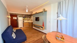 A compact living space with a kitchenette, a sofa, a dining table, and a TV mounted on the wall. - Diamond Beach (Vila Velha)