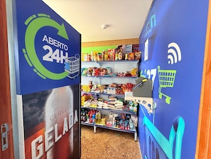 Un pasillo con estantes llenos de diversos productos alimenticios y un letrero que indica tienda abierta las 24 horas.