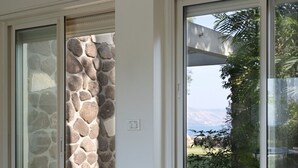 Une pièce avec un mur en pierre, une porte-fenêtre coulissante donnant sur l’extérieur et une vue sur la verdure et les montagnes.