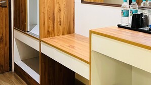 A hotel room with wooden paneling, a large mirror, a vanity with a sink, and a trash can. - Hotel Monarch International (Bengaluru)