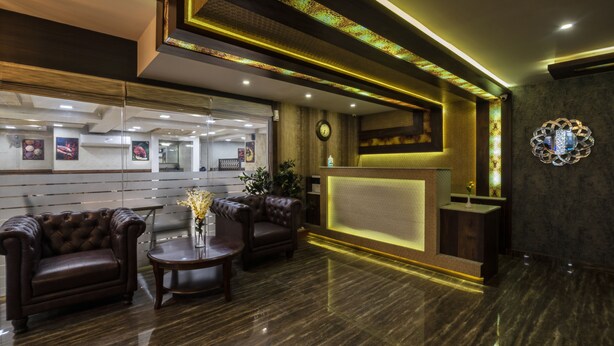 A reception area with leather sofas, a reception desk, and a clock on the wall. - Hotel Monarch International (Bengaluru)