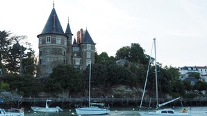 Een historisch kasteel met meerdere torens en uitzicht op het water.