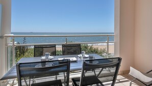 Ein Balkon mit Tisch und Stühlen mit Blick auf einen Strand.