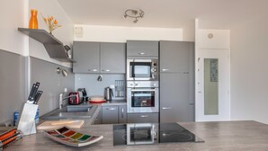 Eine moderne Küche mit grauen Schränken, einer integrierten Mikrowelle, einem Backofen und einer schwarzen Induktionskochplatte.