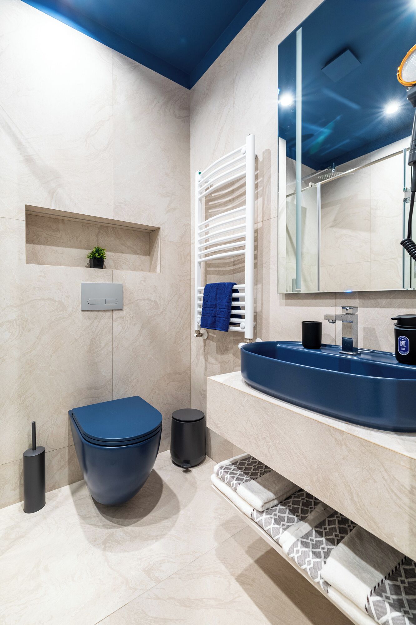 Une salle de bain moderne avec un lavabo bleu, des toilettes et un miroir.