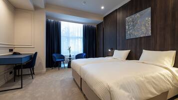 A hotel room with a bed, a desk, and a chair.