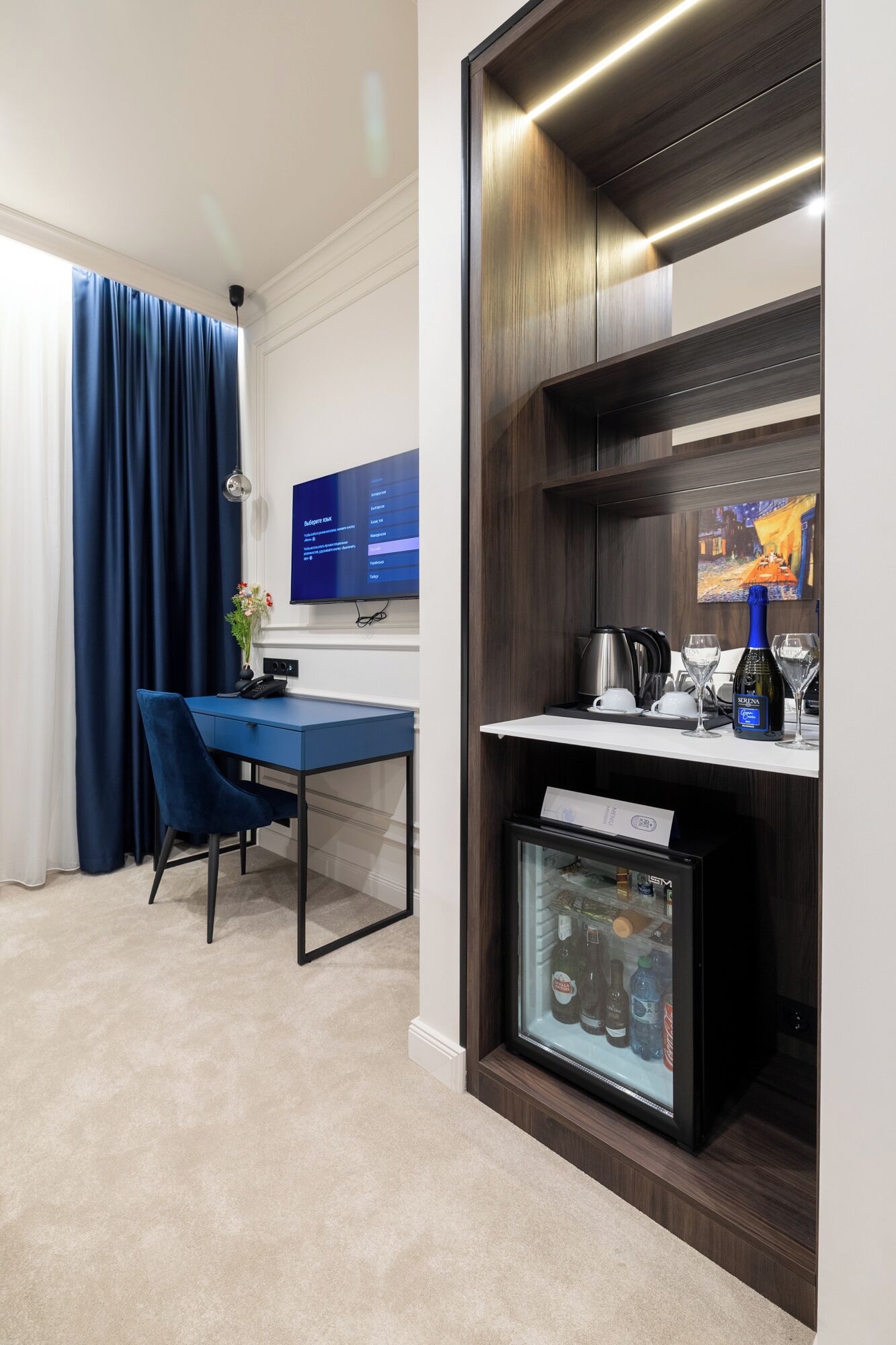 A hotel room with a desk, chair, and a minibar.