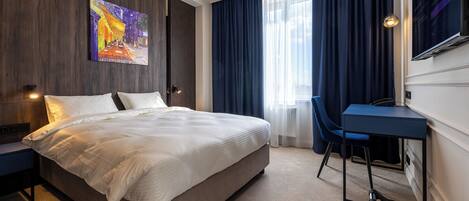A modern hotel room with a large bed, a desk, and a chair.