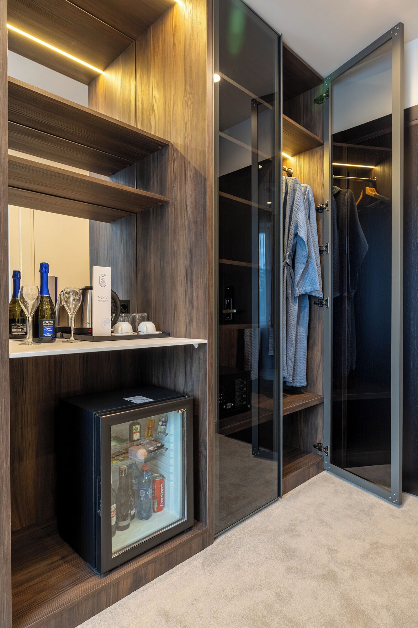 A modern walk-in closet with wooden shelving, a minibar, and a glass door closet.
