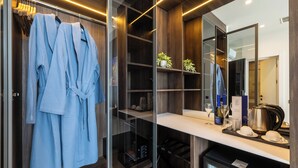 A modern bathroom with a glass shower enclosure, a robe rack, a vanity with a mirror, and a minibar. - Art Hotel (Chisinau)