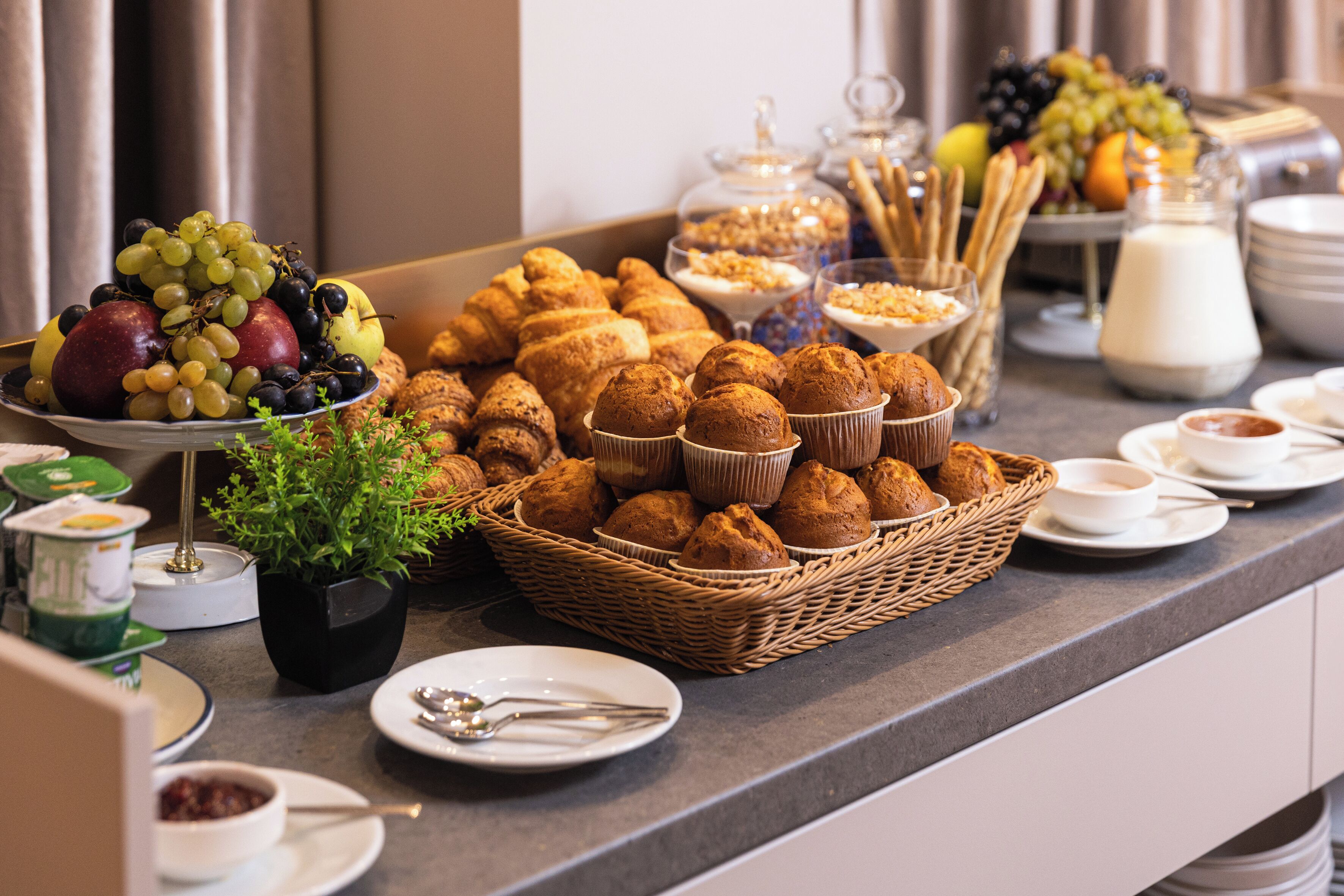 A buffet with various food items including fruits, pastries, and dairy products.