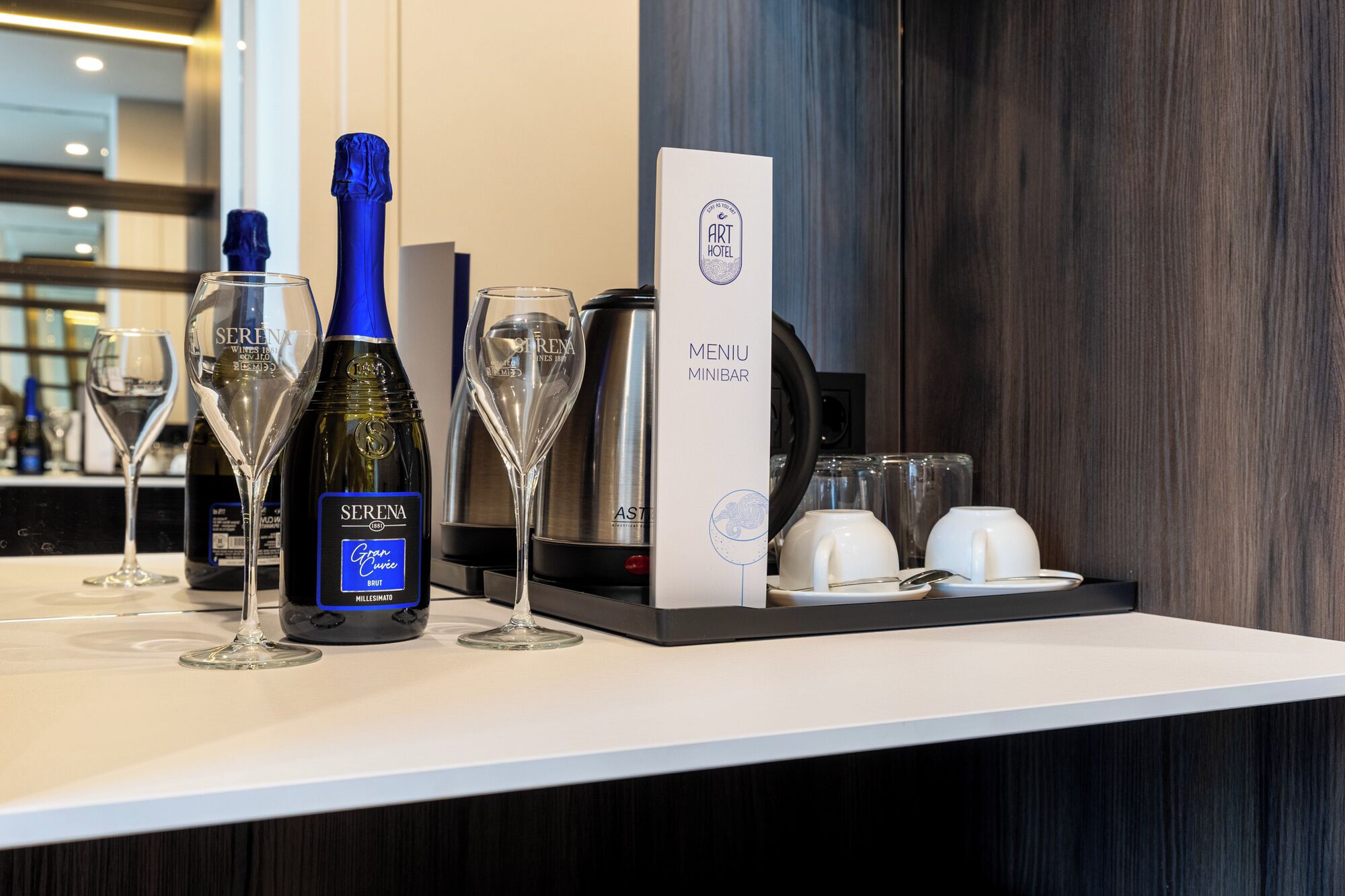 A minibar setup with a bottle of Serena wine, glasses, and a mini-bar sign.