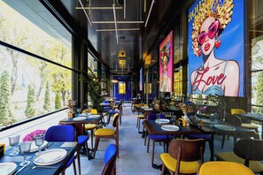 Un restaurant avec des tables dressées, des chaises et une grande fresque murale.