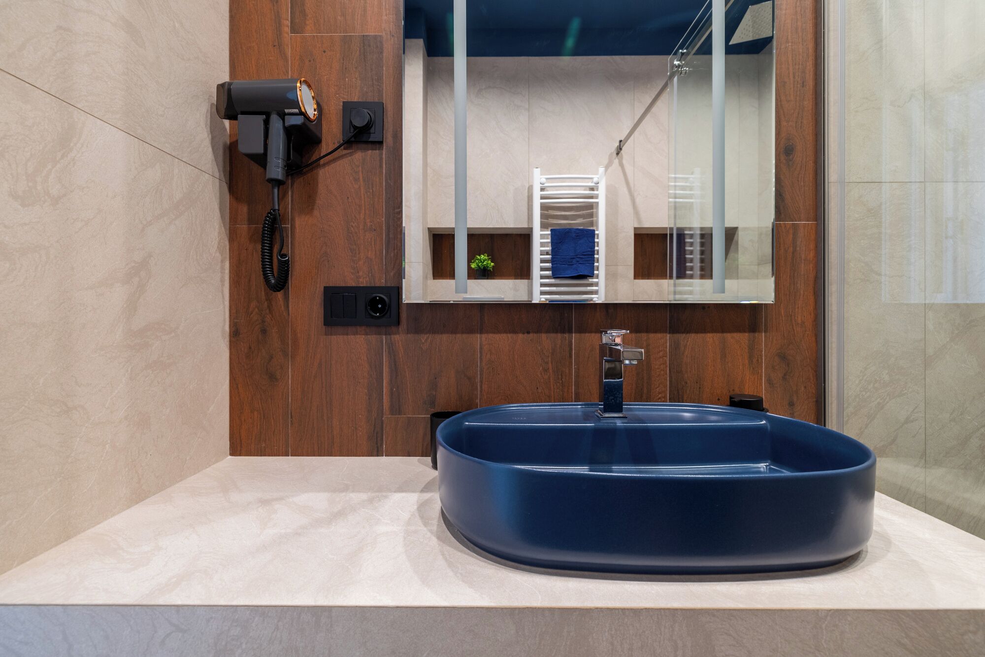 Un baño con un lavabo azul, un secador de pelo y un perchero para toallas.