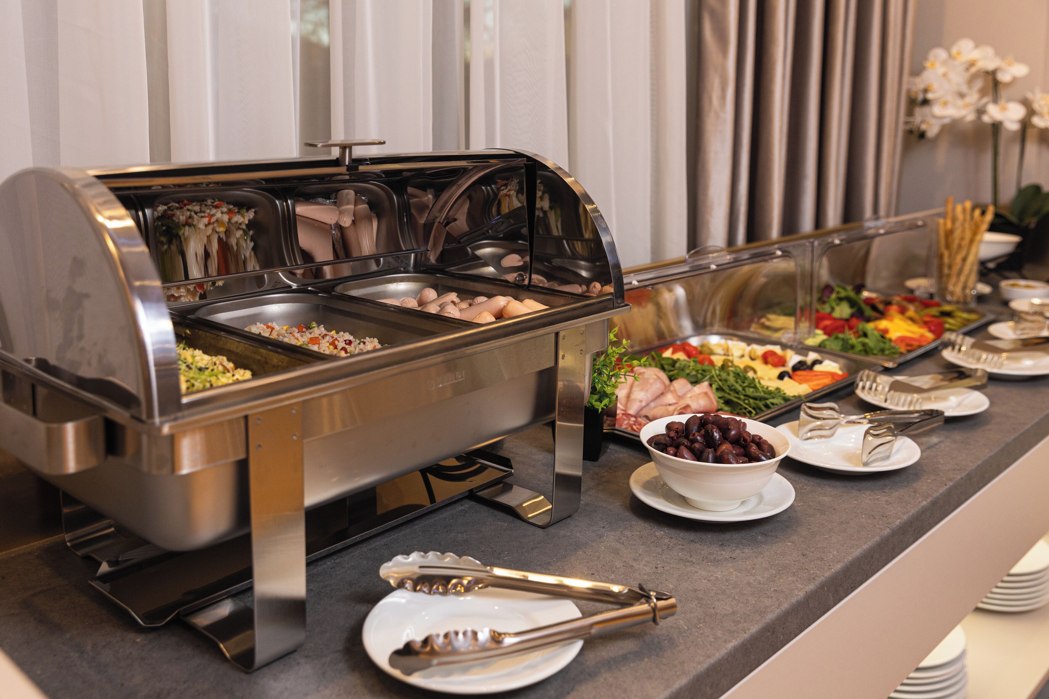 A buffet setup with various food items and utensils.