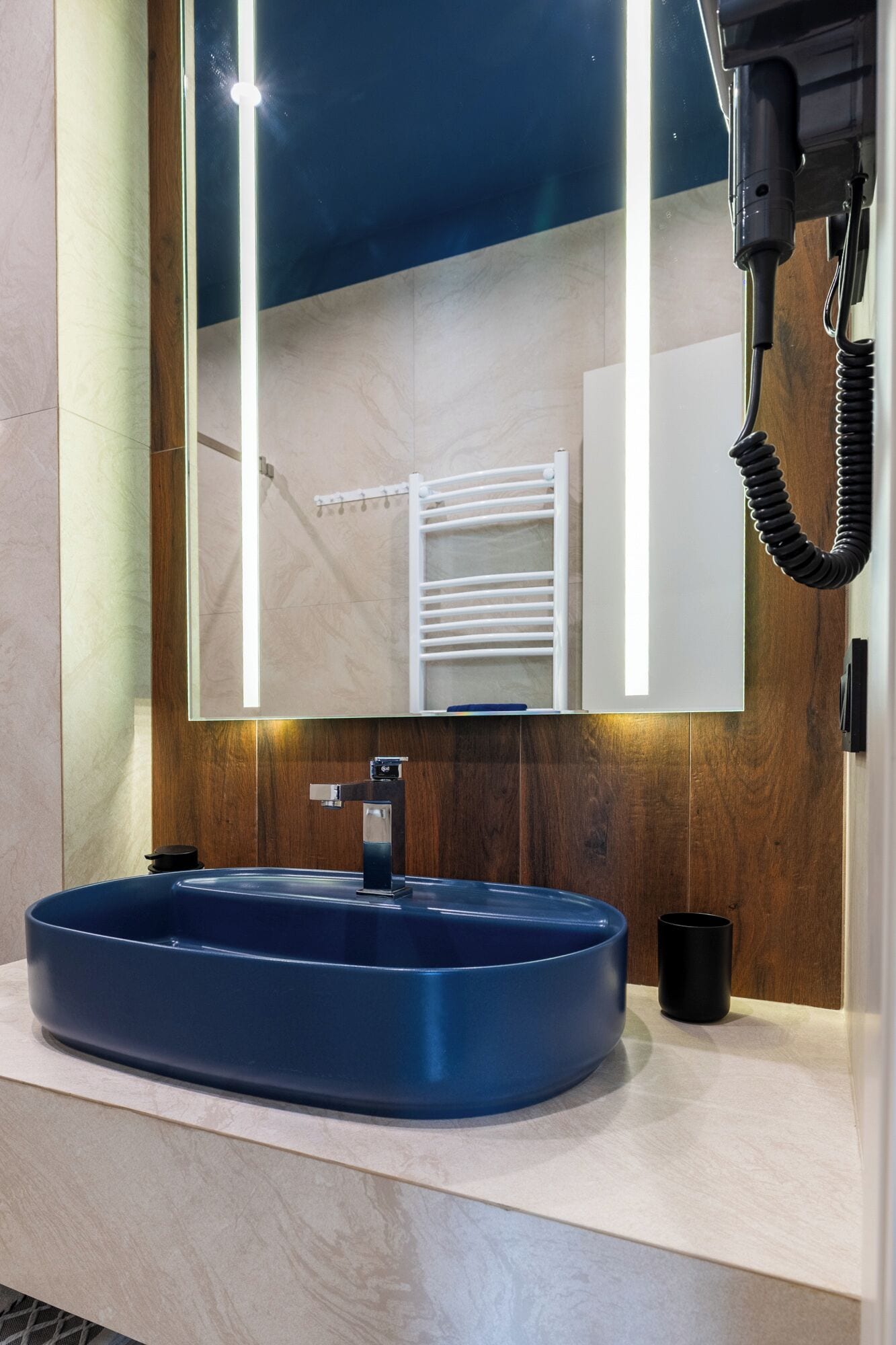 Um banheiro moderno com um espelho grande, uma pia azul e um porta-toalhas.