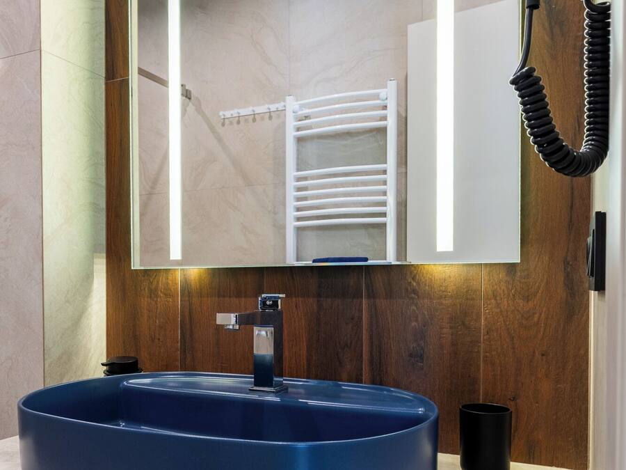Um banheiro moderno com um espelho grande, uma pia azul e um porta-toalhas.