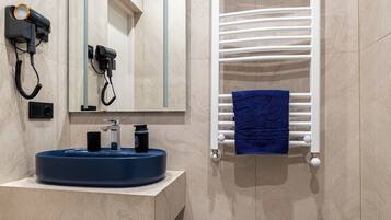 Un baño moderno con lavamanos empotrado, un perchero con una toalla azul y un espejo.