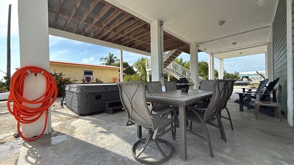 Une terrasse extérieure avec une table et des chaises, un jacuzzi et un barbecue.