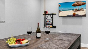 A dining area with a table set for two, featuring a bottle of wine, glasses, and a fruit platter. - Heated Pool & Game Room, Sleeps 10 | 5 Min to Busch Gardens, Tampa (Tampa)