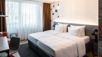 A modern hotel room with a large bed, a desk, and a chair.