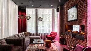 Ein modernes Wohnzimmer mit einer Eckcouch, einem roten Sessel, einem kleinen Tisch und einem Kamin mit Backsteinwand.