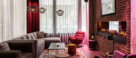 A modern living room with a sectional sofa, a red armchair, a small table, and a fireplace with a brick wall.