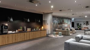 Eine moderne Hotellobby mit einem Holzbuchtschrank, einer Sitzecke und einem Wandgemälde.