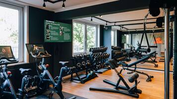 Un gimnasio con bicicletas estáticas, mancuernas y máquinas de pesas.