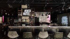 Ein Barbereich mit einem 'PENTA HOTEL' Schild, Barhocker und einer Auswahl an Flaschen.