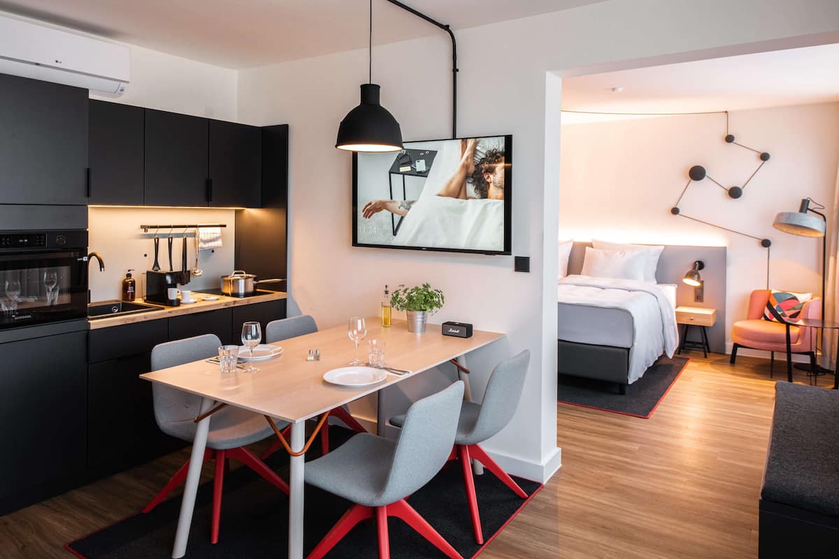 A modern kitchen with a dining area, a bed, and a small living space.