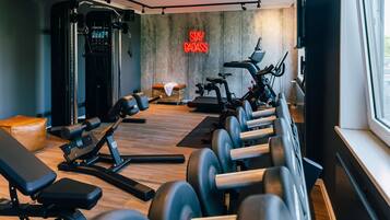 A gym with exercise equipment, a treadmill, and a neon sign.