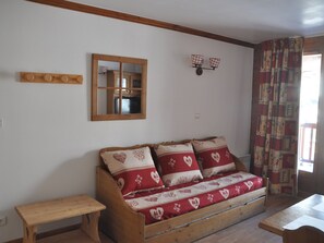 Ein gemütliches Zimmer mit einer Holzsofa, einer hölzernen Bank, einem Spiegel und einem an der Wand montierten Regal mit Körben.
