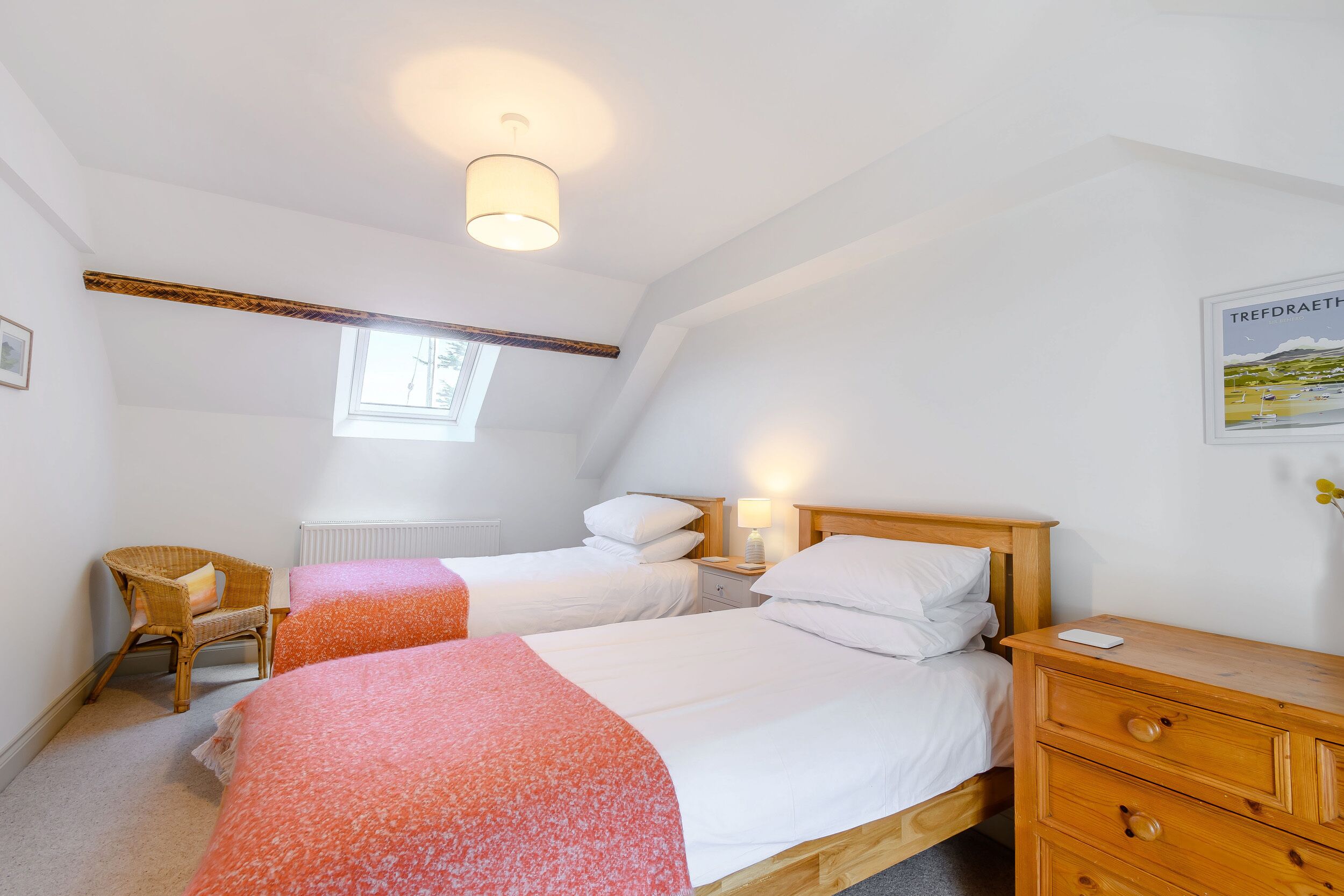 Un dormitorio con dos camas, un aparador de madera, una silla, un ventanal y un cuadro en la pared.