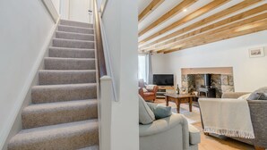 Una escalera conduce a una sala de estar con chimenea, un sofá y una televisión.