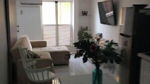 Ein Wohnzimmer mit einer Couch, einem Esstisch und einem an der Wand befestigten Fernseher.