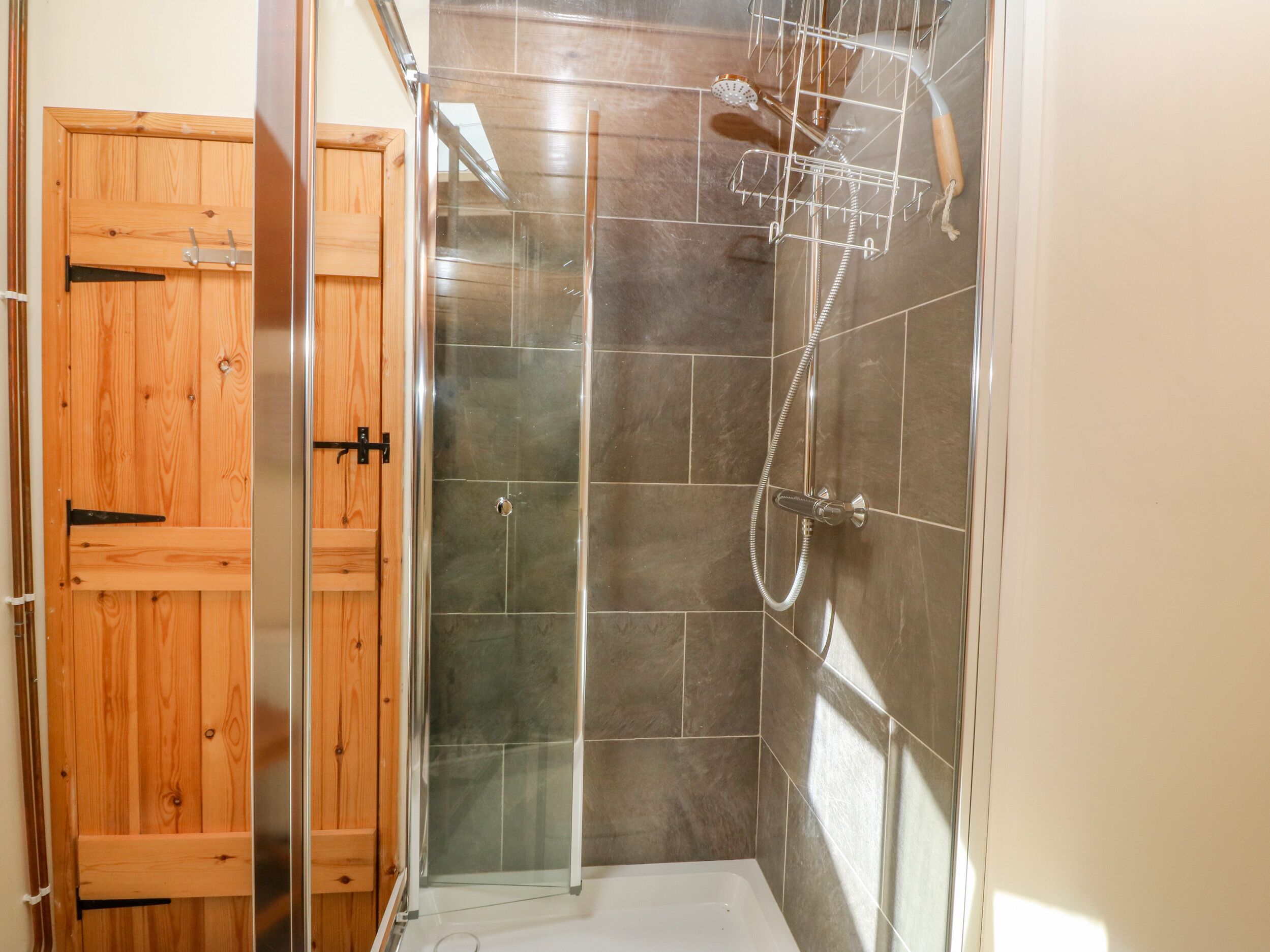 Eine Dusche mit Glastür, Duschkopf und Handbrause.