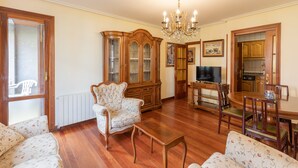 A living room with a wooden cabinet, a television, and a dining area with chairs and a table. - Plaza berri - baskeyrentals (Azkoitia)