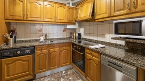 A kitchen with wooden cabinets, a granite countertop, a dishwasher, an oven, and a microwave. - Plaza berri - baskeyrentals (Azkoitia)