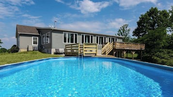 A residential swimming pool with a house in the background.