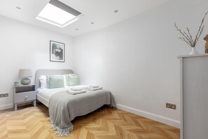 Quarto com cama, mesa de cabeceira, abajur e prateleira na parede com um vaso.