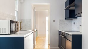 Een moderne keuken met witte kasten, een oven van roestvrij staal en een magnetron.